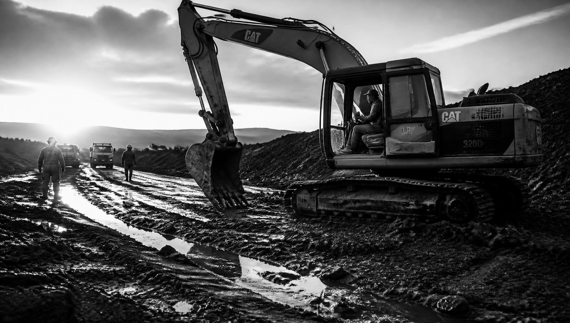 Excavator and crew working a site at dusk